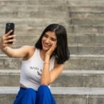 a woman sitting on steps taking a picture with her cell phone