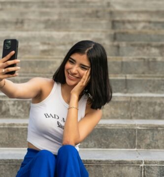 a woman sitting on steps taking a picture with her cell phone